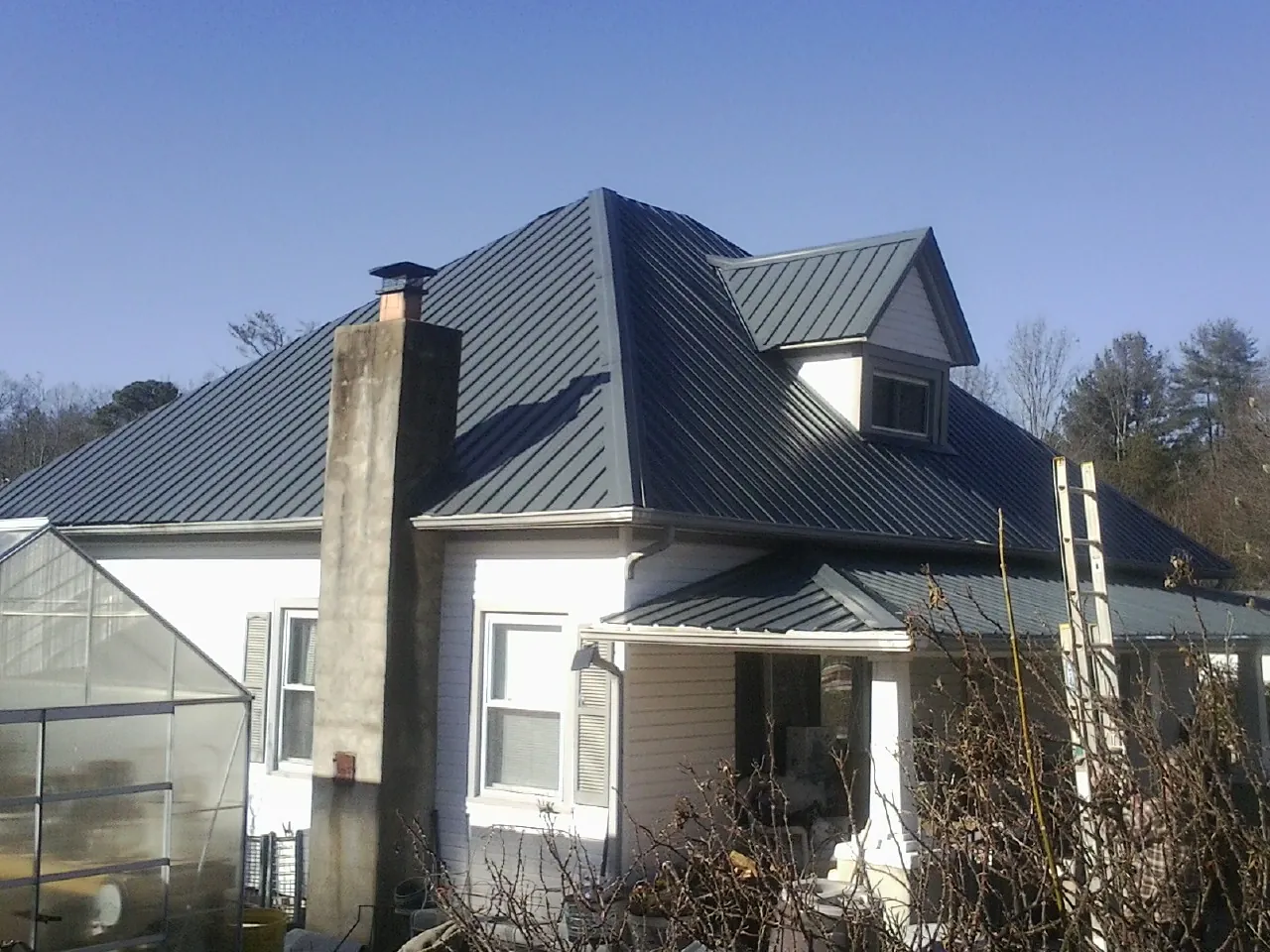 Dark blue standing seam metal roof on a white farmhouse with dormer — Slate & Tile Roof Repair by Roofing Brothers in Brandywine