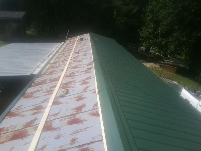 Old rusted panels beside newly installed green metal roofing — Wind Damage Roof Repair by Roofing Brothers in Brandywine